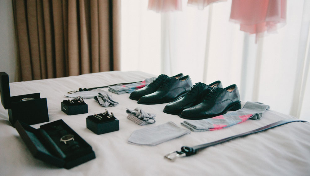 Wedding shoes, watch, tie, and belt on bed